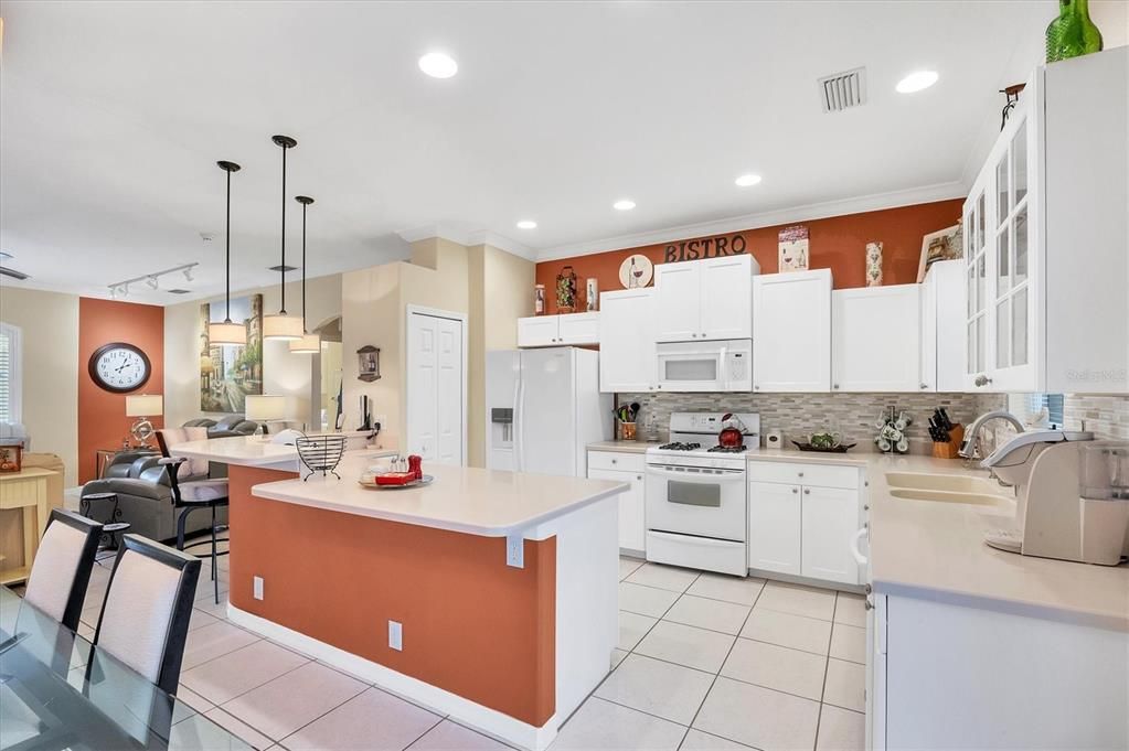 Spacious kitchen is highlighted with a gas stove, decorative tiled backsplash & solid surface counters