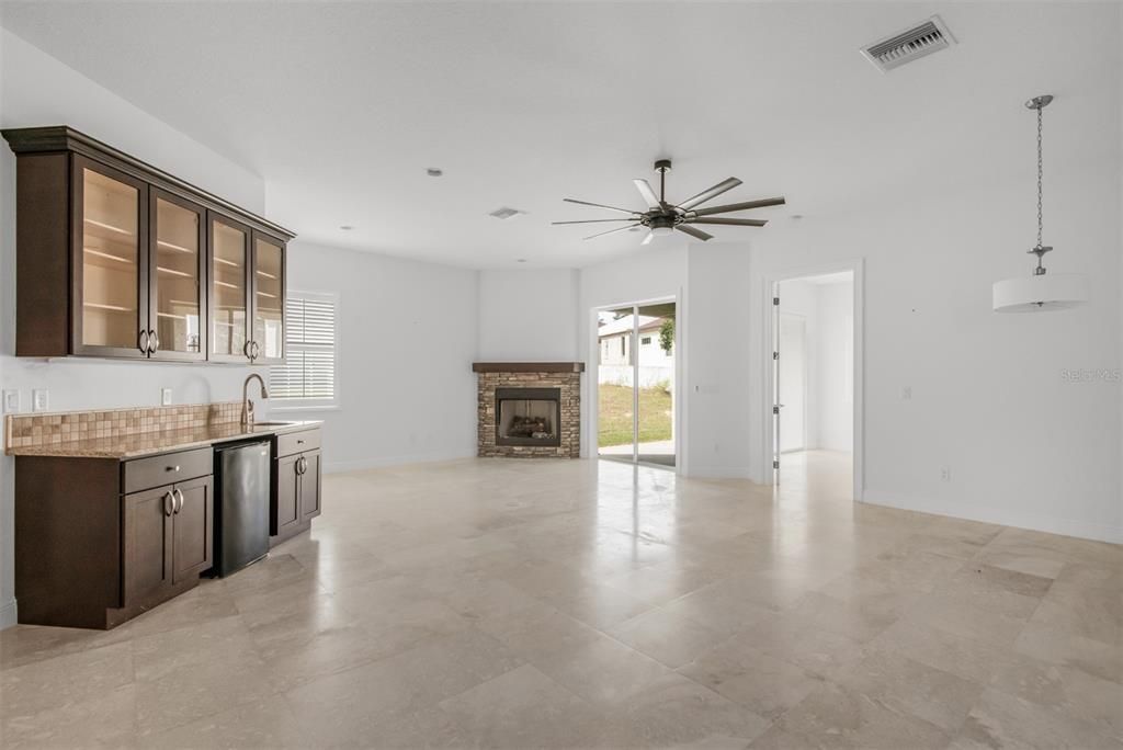 Wet-bar with fridge and upper lighted cabinets with glass doors