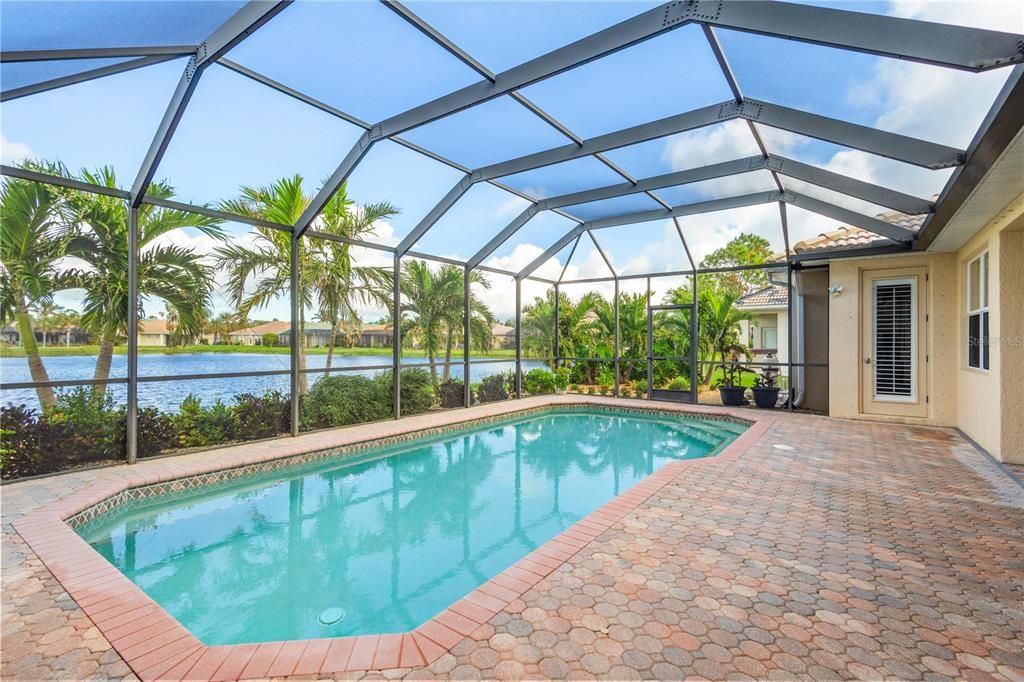 Paver lanai and pool and sitting area overlook beautiful pond