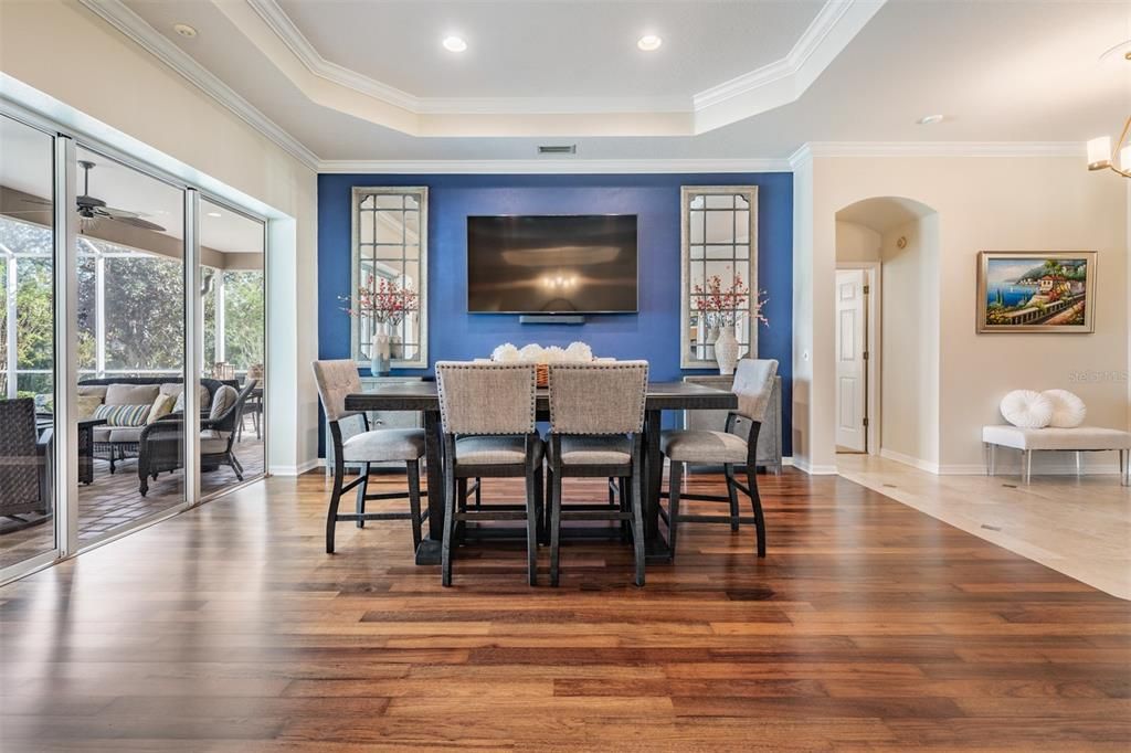 Spacious Dining Room with Burma Walnut Flooring, Inset Ceiling with crown molding, overlooking the pool area.