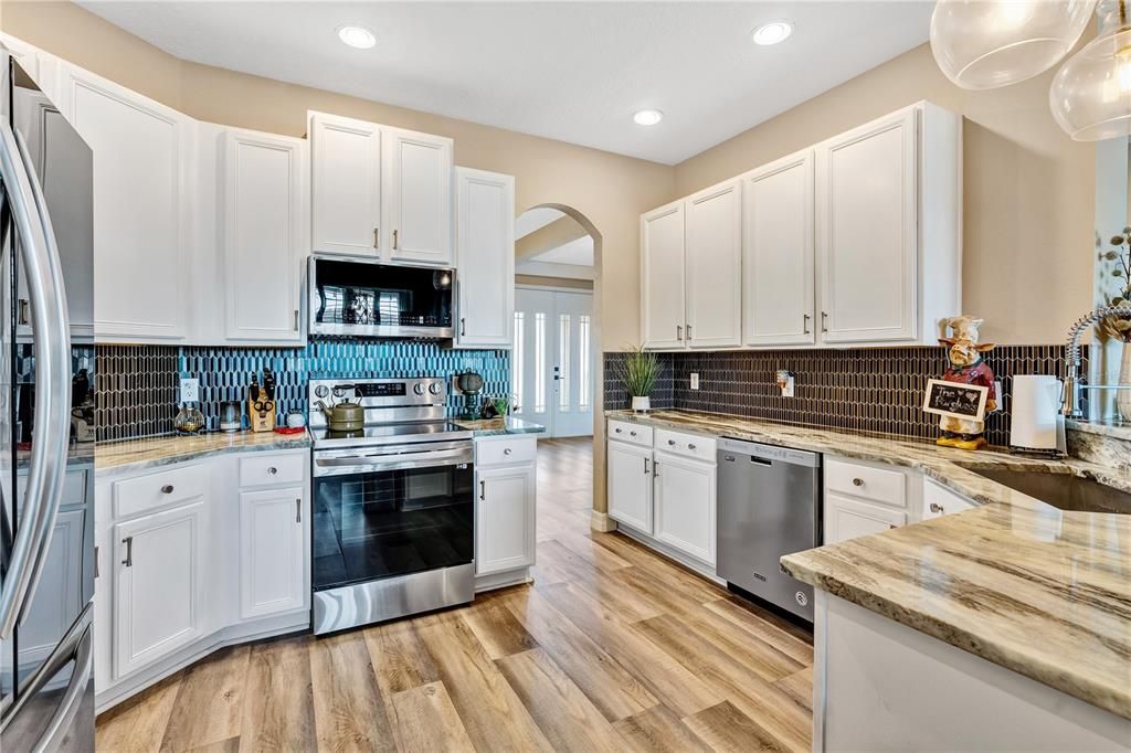 Open kitchen with stainless steel appliances, gorgeous stone countertops, recessed lighting and