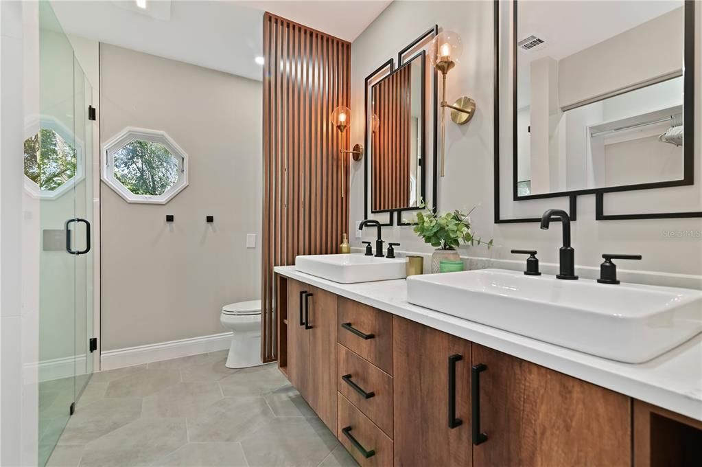 Mid-Century Modern Master Bathroom features double sinks with matte black faucets. Slat wall divider for privacy. Plenty of cabinet space for storage.