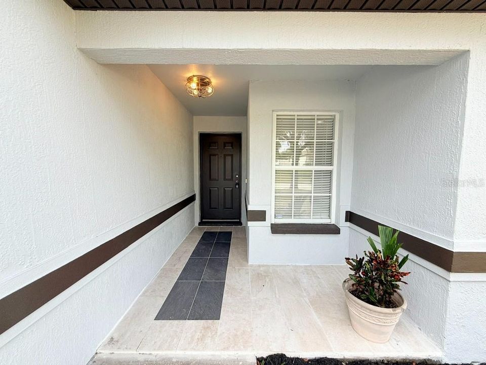 Tiled walkway to at covered front door entrance.