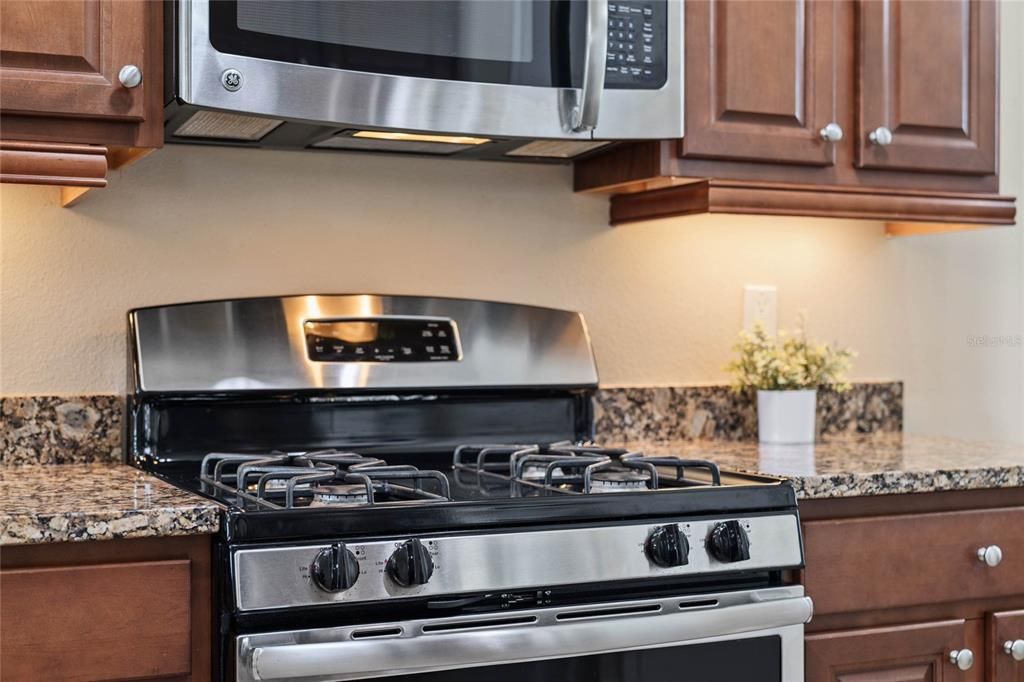 Stainless steel 4-burner natural gas range w/ microwave above that vents to exterior of home