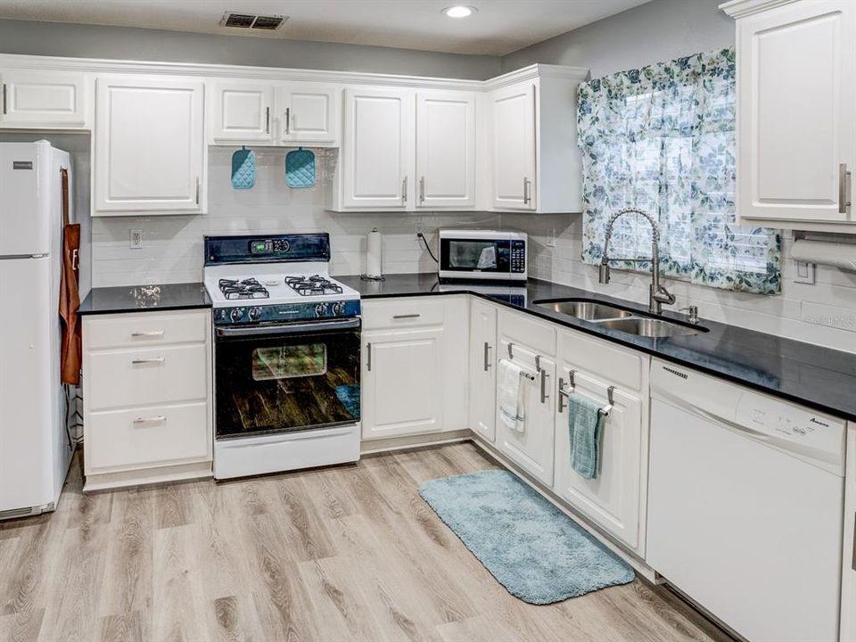 Kitchen with black granite counter tops. Gas stove.