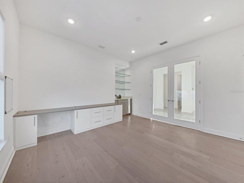 den looking towards double doors, built in desk space