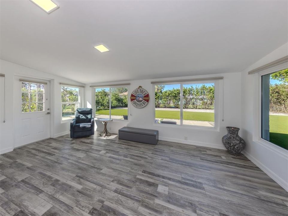 Large Florida room with its own entrance, hurricane impact windows, cohesive luxury flooring, and custom Levolor cellular window treatments.