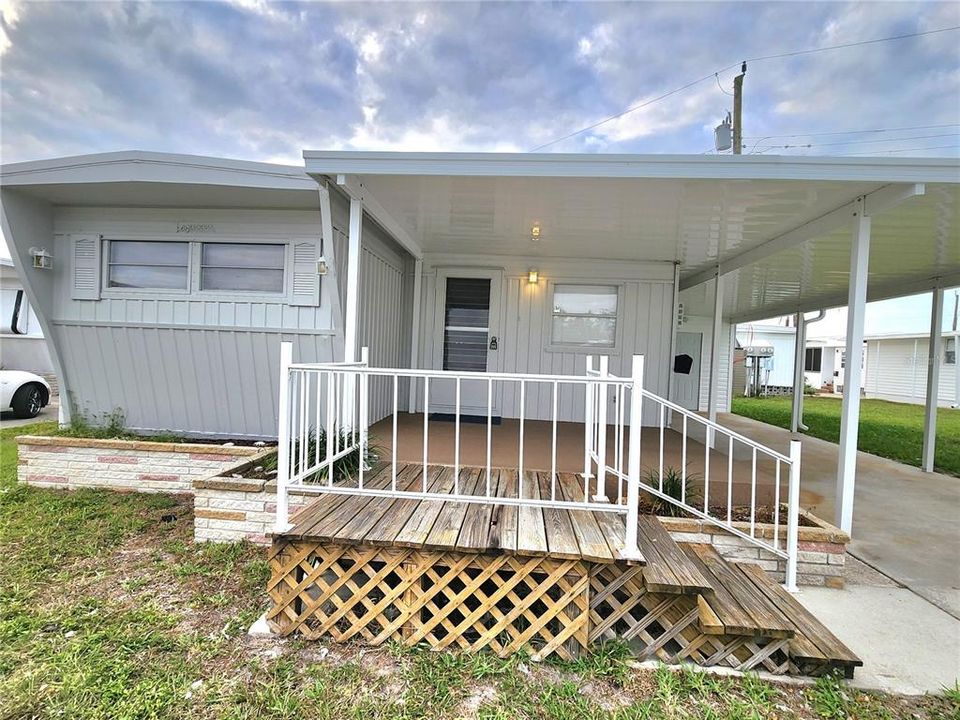 porch with extended wooden deck and stairs with handrail.