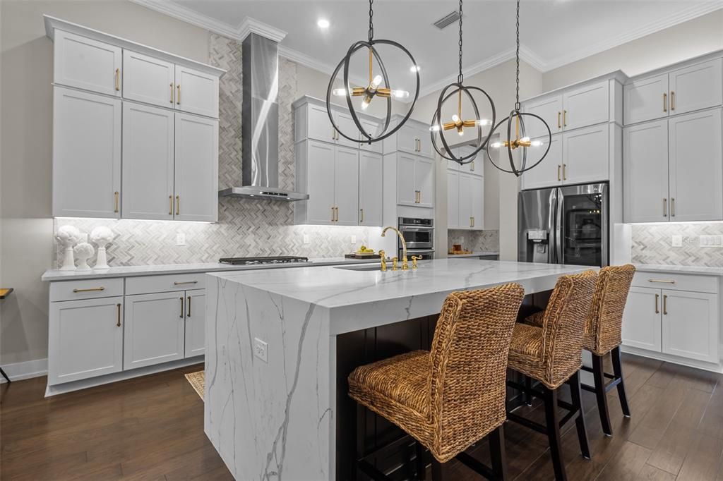 Kitchen - waterfall, quartz island, stacked cabinets, built in stainless steel appliances