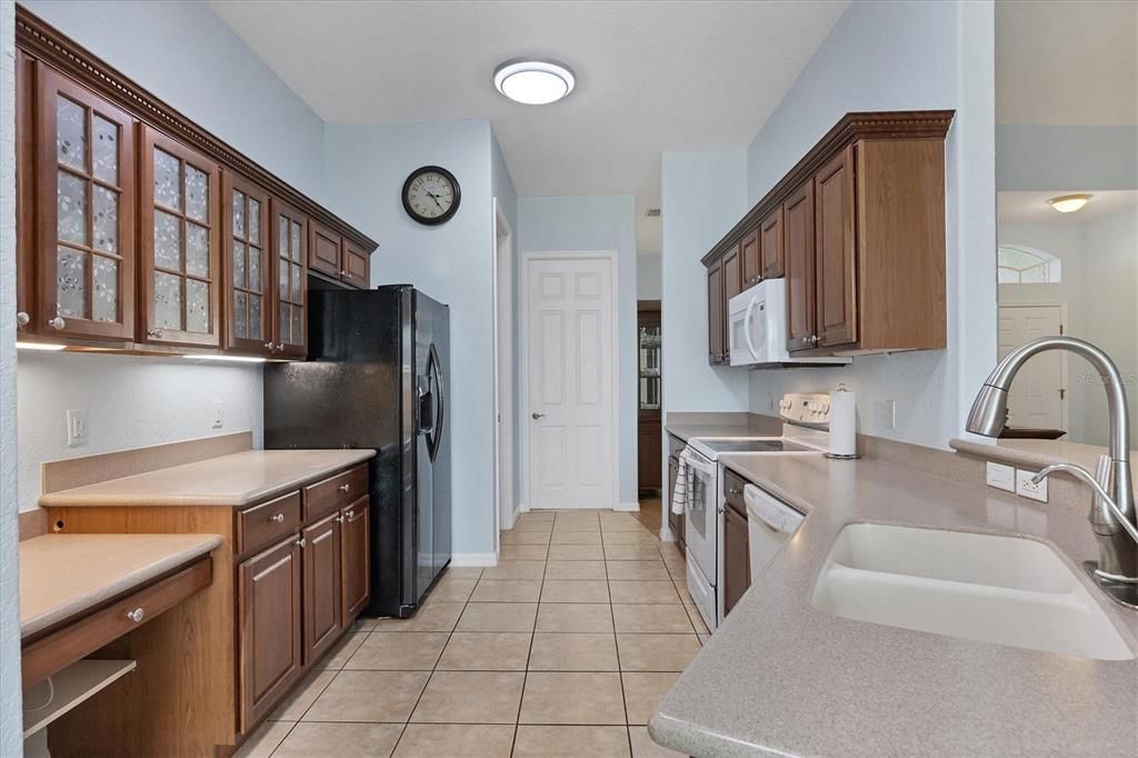 LOOKING TOWARDS FRONT FROM EAT IN AREA OF KITCHEN-BUILT IN DESK, SOLID SURFACE COUNTERTOPS, ETCHED FRONTS ON CABINETS TO LEFT SIDE