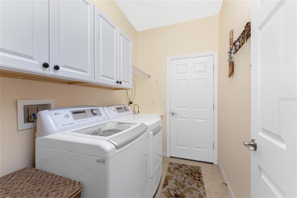 The utility room has tiled flooring, cabinetry for storage, a utility sink and newer LG washer and dryer.