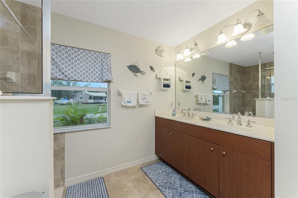 A raised height vanity with a cultured marble top and double basins provides plenty of storage.