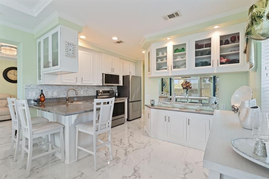 kitchen with quartz countertops, solid wood cabinets, stainless steel appliances, breakfast bar and built in hutch