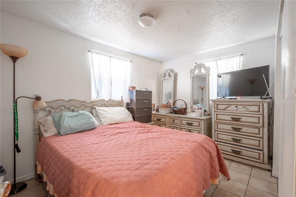 UNIT A: 1st bedroom features a ceramic tile floor, neutral tones and a built-in closet