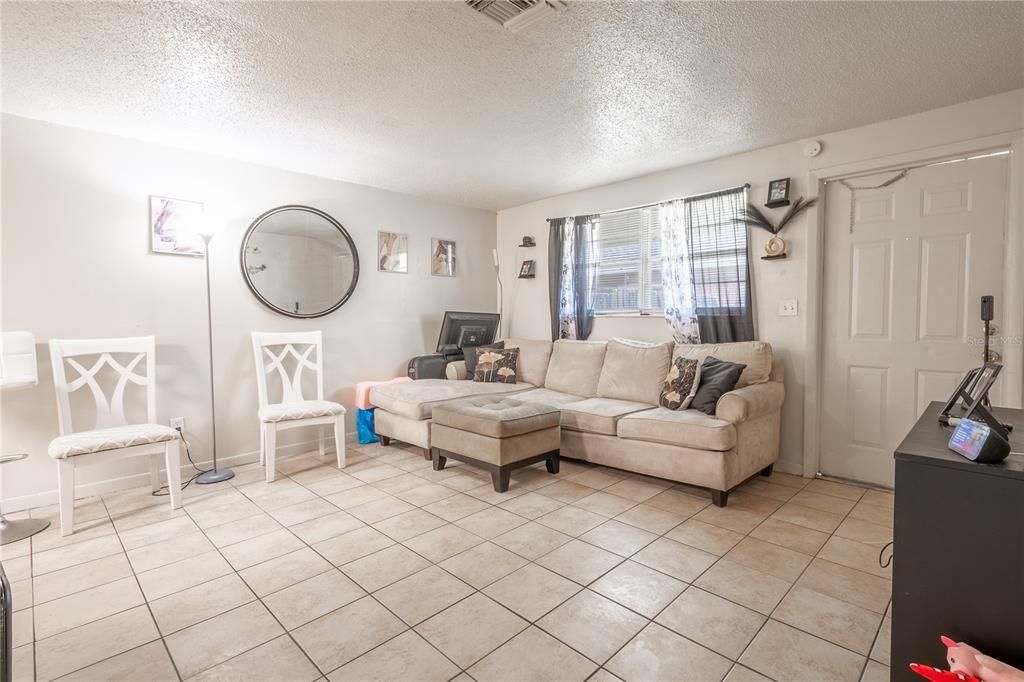 UNIT B: Living room features neutral tones and ceramic tile floor.