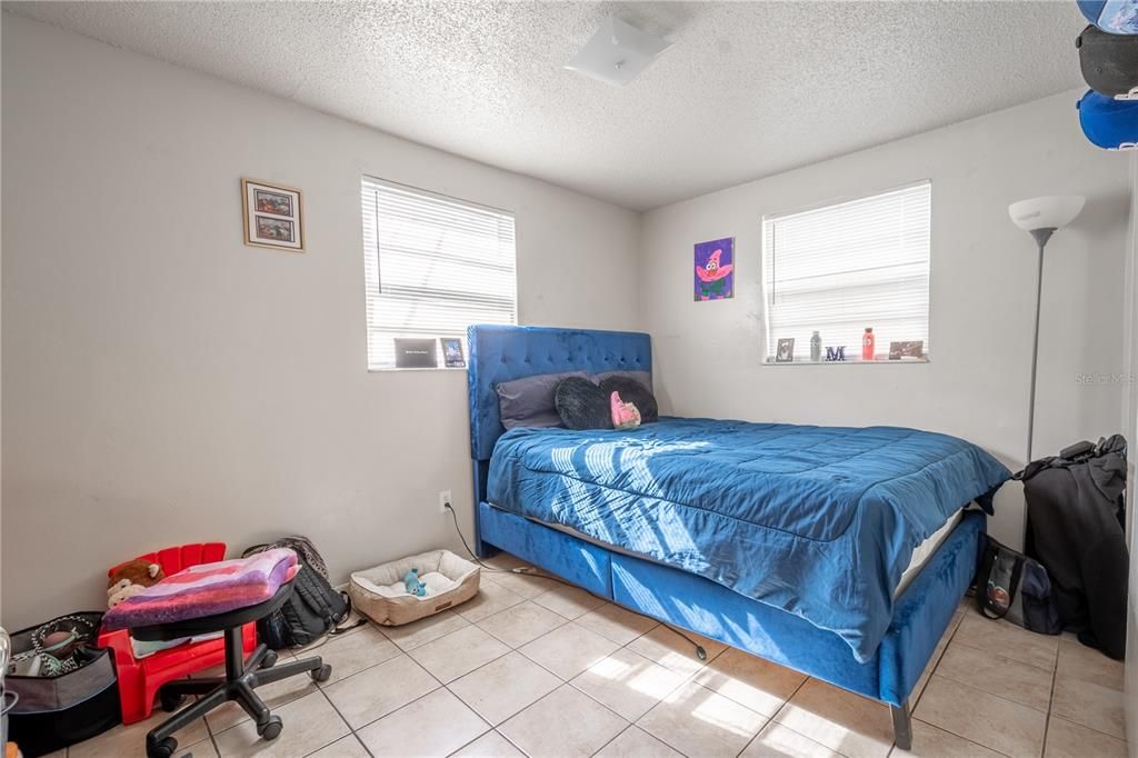 UNIT B: 1st bedroom features a ceramic tile floor, neutral tones and a built-in closet