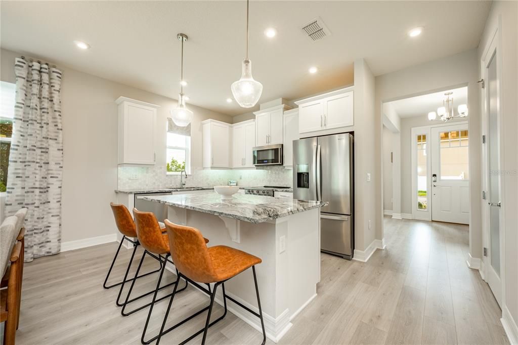 The kitchen was thoughtfully designed with the home chef in mind and delivers UPGRADED STAINLESS STEEL APPLIANCES, a decorative tile backsplash, 42” SHAKER STYLE CABINETRY topped with crown molding, QUARTZ COUNTERTOPS, and breakfast bar seating on the large ISLAND for casual dining or entertaining.