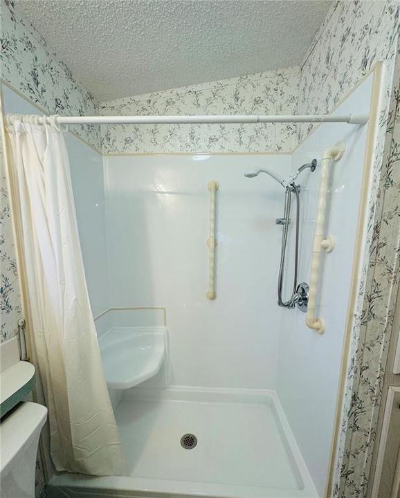 Shower in primary bathroom with seat & grab bar