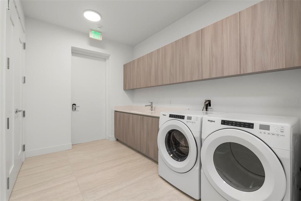 The large in-unit laundry room featuring ample cabinetry and large capacity, front load Whirlpool washer and dryer