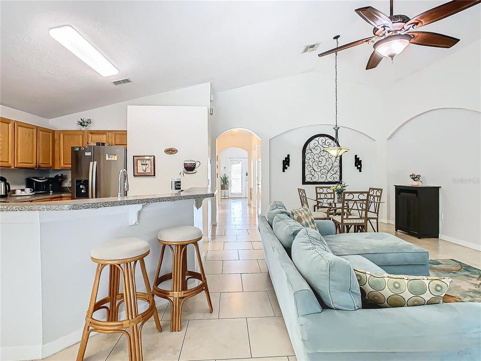 A view of the kitchen and breakfast bar, the living room, and the dining room looking toward the front door.