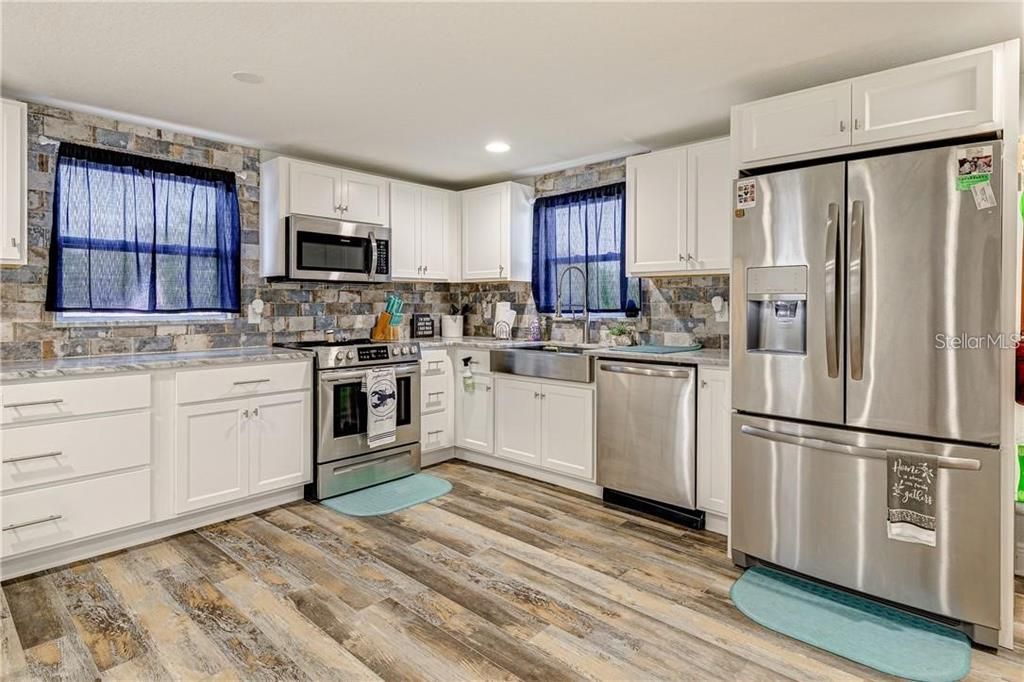 kitchen with granite countertop and matched tile back splash and all stainless-steel appliances