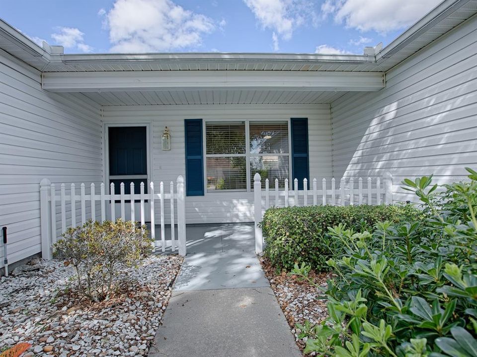 INVITING FRONT PORCH FINISHED RECENTLY WITH EPOXY FLOOR, WHITE PICKET FENCE, NEW SCREEN DOOR AND LOVELY NEW BRASS LIGHT FIXTURE.