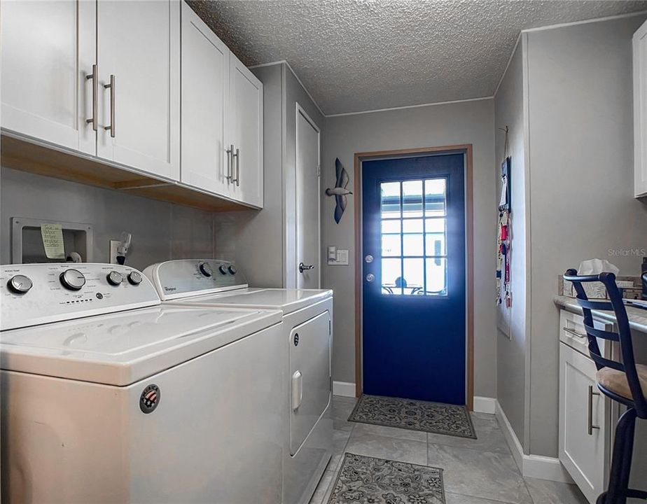 Back entrance to laundry room with storage cabinets and two closets