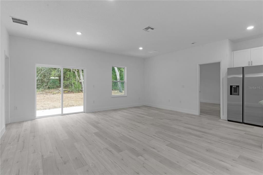 From dining area across living room. The door beside the refrigerator leads into primary suite.