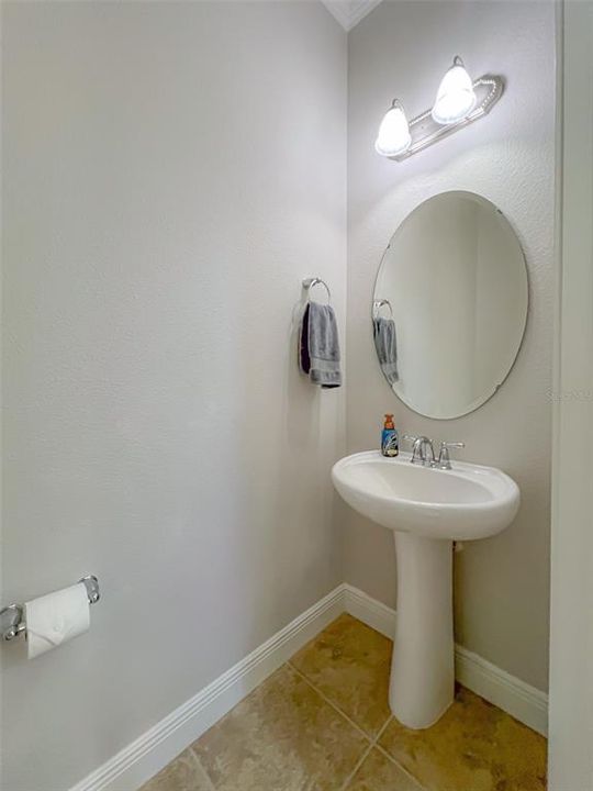 Convenient half-bathroom with pedestal sink and crown molding and new Kohler toilet