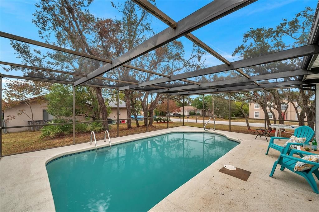 Serene view from the screened pool enclosure to the spacious backyard—perfect for blending outdoor relaxation and natural beauty.