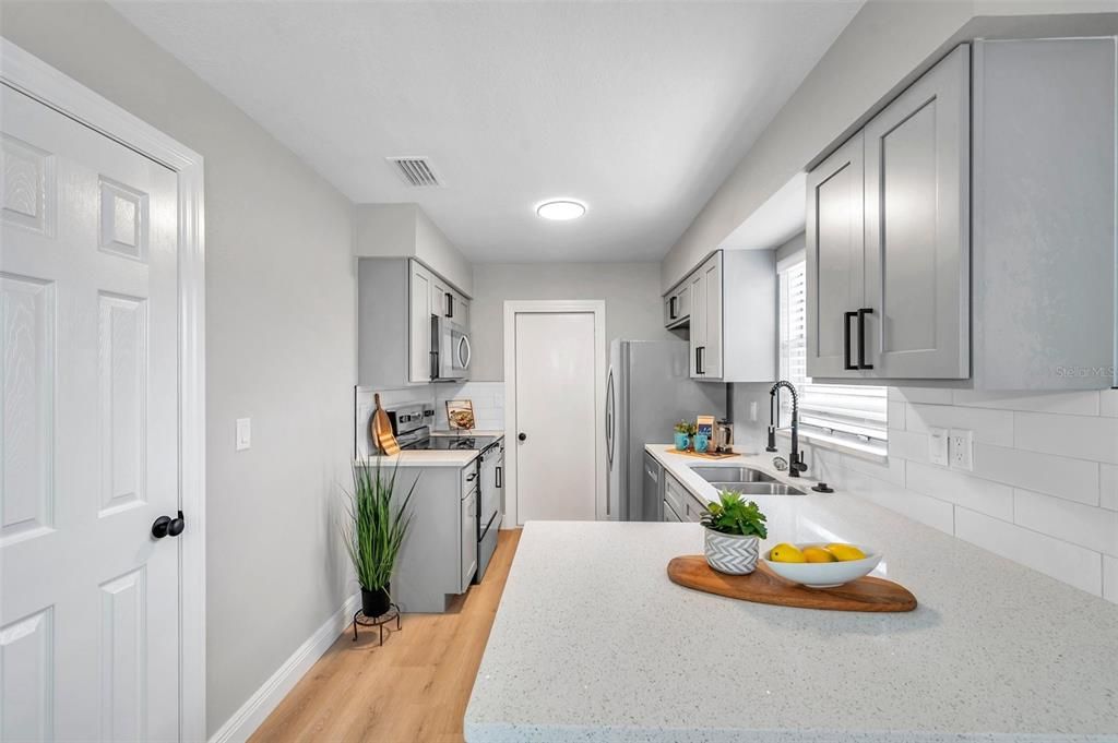 Modern kitchen with a convenient breakfast bar, a closet pantry for extra storage, and easy access to the garage—designed for style and functionality!