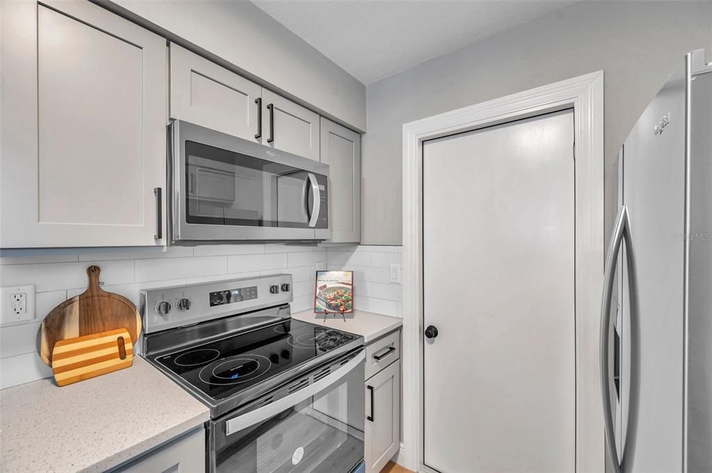 kitchen view featuring brand-new stainless steel appliances, including a microwave, range, and refrigerator, with convenient access to the garage—perfectly blending style and efficiency