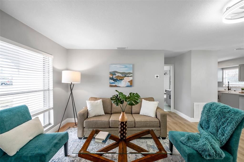 Bright and inviting living room with seamless views of the hallway leading to the guest bath and bedroom, plus easy access to the modern kitchen—designed for comfort and functionality!