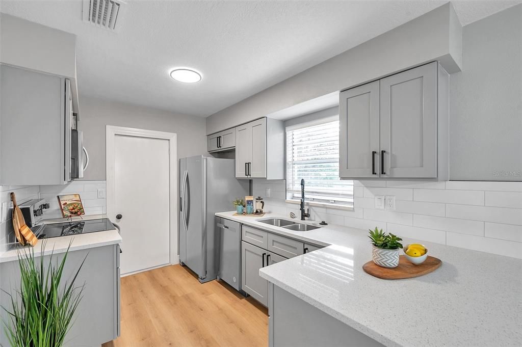 Fully remodeled kitchen featuring sleek gray shaker cabinets with soft-close functionality, a stylish over-the-sink window offering picturesque views of the pool and backyard—designed for both beauty and practicality!