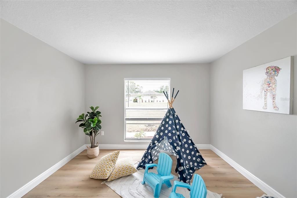 Another angle of the versatile second bedroom, featuring a front-facing window with a lovely view of the yard—window will be replaced or credit provided at closing.