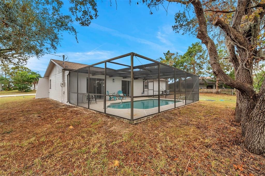 Side yard offers additional outdoor space with easy access to the screened pool—perfect for gardening or storage