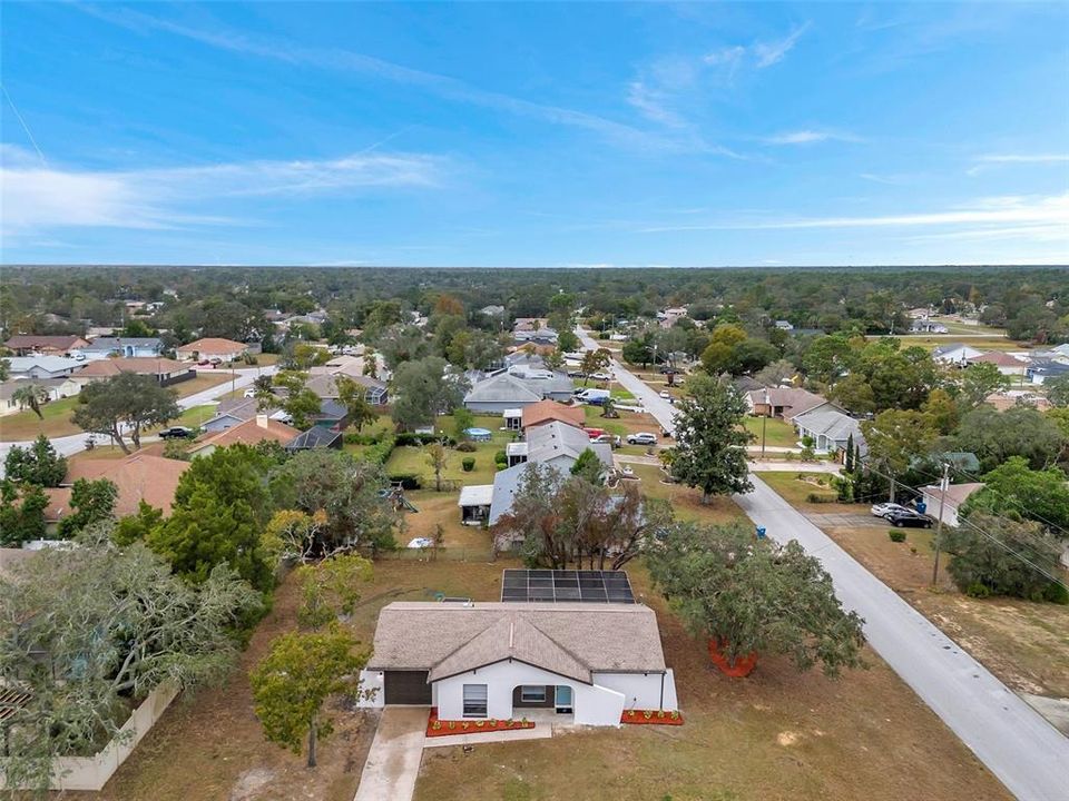 Stunning aerial view showcasing the expansive property, including the large yard, home, and screened pool enclosure.