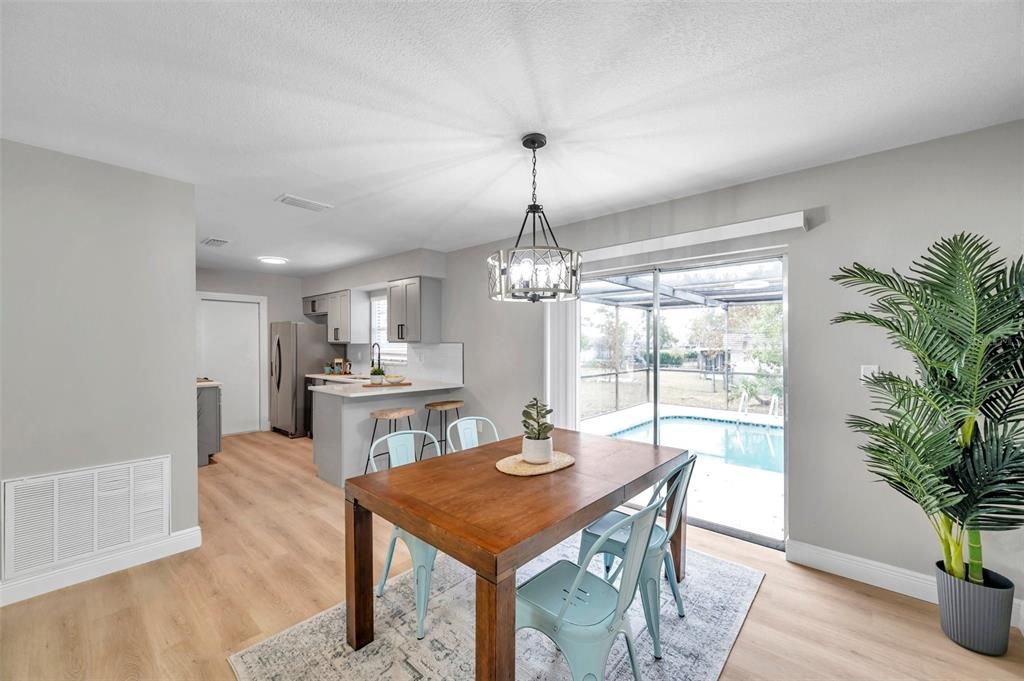 Spacious dining room with a clear view of the kitchen and sliding glass doors leading to the pool area—ideal for entertaining and enjoying indoor-outdoor living.