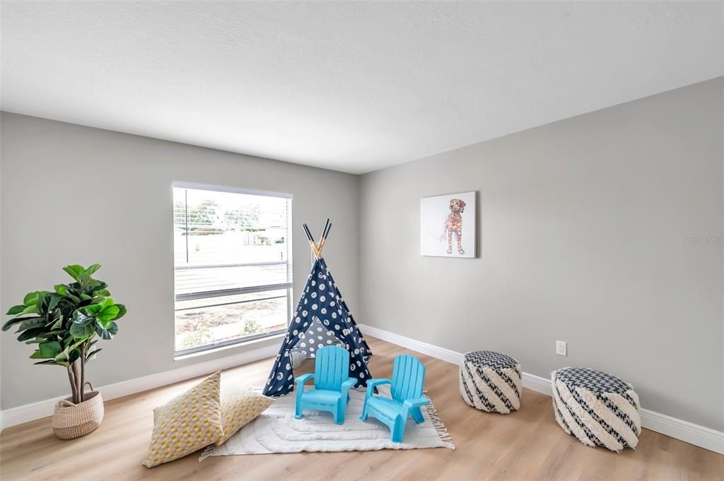 Charming second bedroom currently staged with a playful teepee, and cozy rug—versatile space perfect for an office, guest room, craft room, second bedroom, or even a man/woman cave