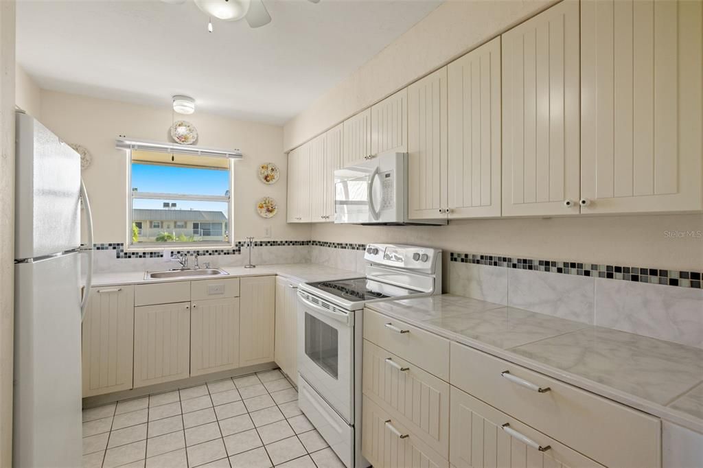 Kitchen featuring ceiling fan, light tile patterned flooring, white appliances