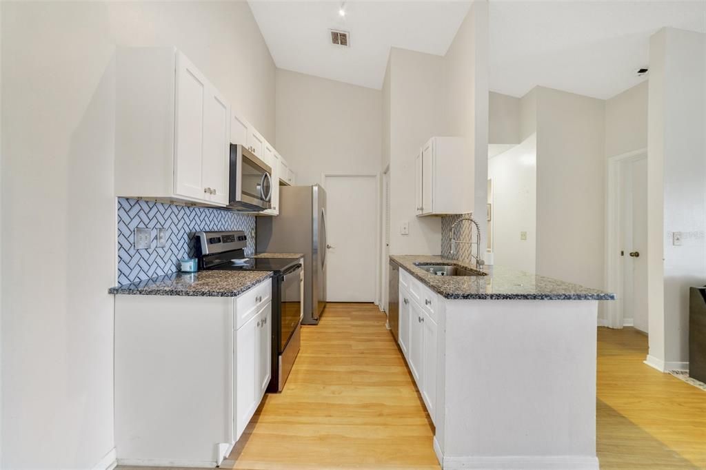 Thoughtfully updated with the home chef in mind, the kitchen features desirable SHAKER STYLE CABINETRY, STAINLESS STEEL APPLIANCES, GRANITE COUNTERS and a tiled backsplash set in a stylish herringbone pattern.