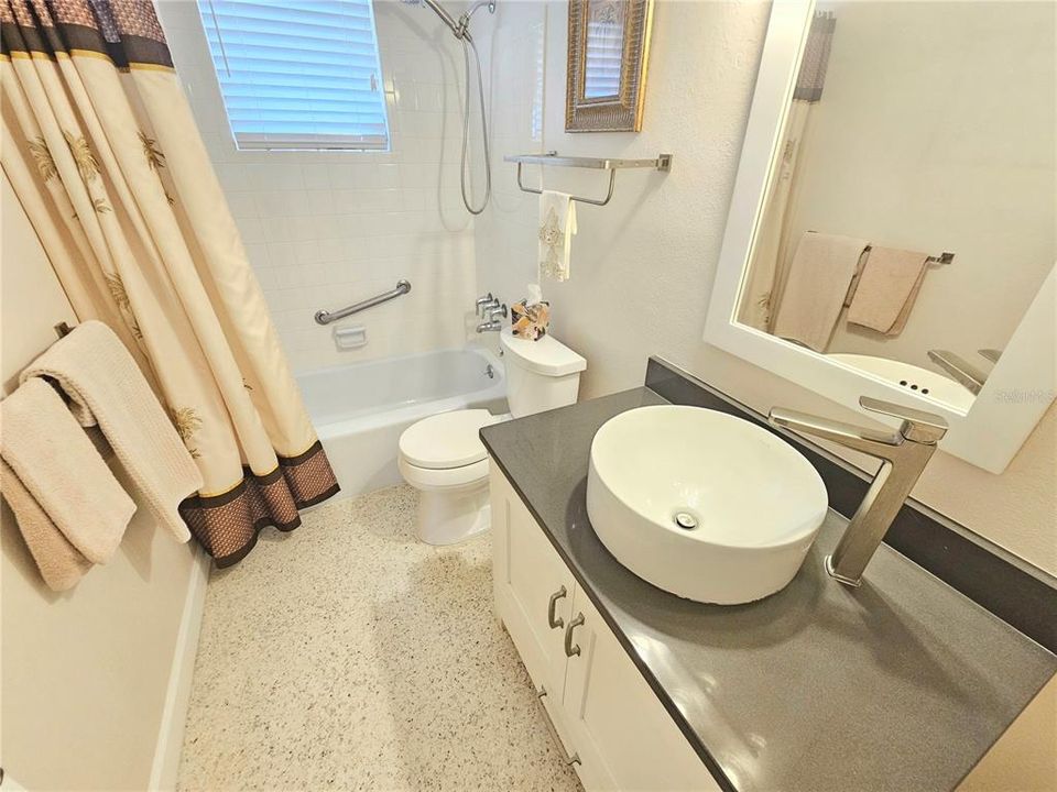 Main bathroom with tub and shower and solid surface counter