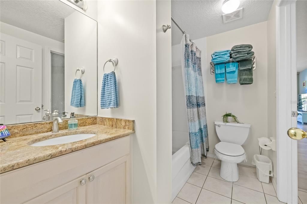 Full bathroom with shower/tub and granite counters.