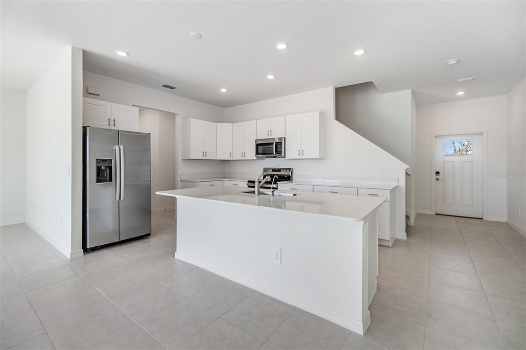 Center Island/breakfast bar with sleek quartz countertops is the focal point