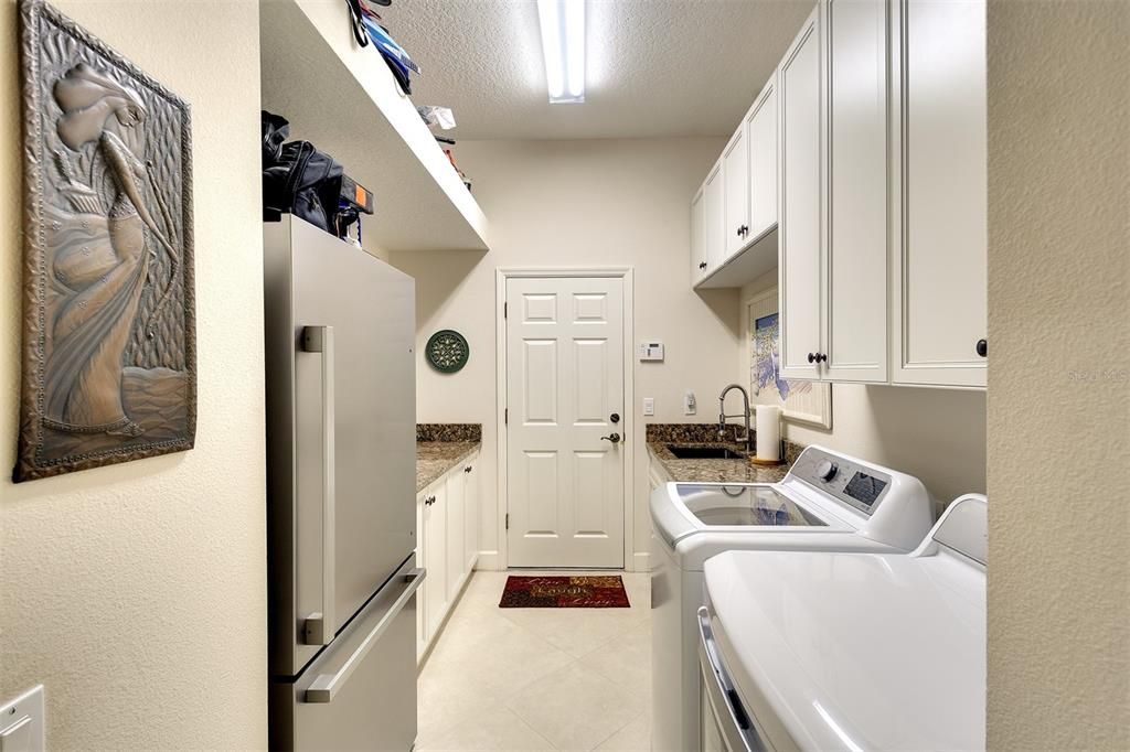 Large laundry room with granite ccounter and newer washer and dryer.