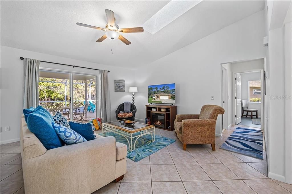 Living room with ceiling fan and sliders to pool and patio