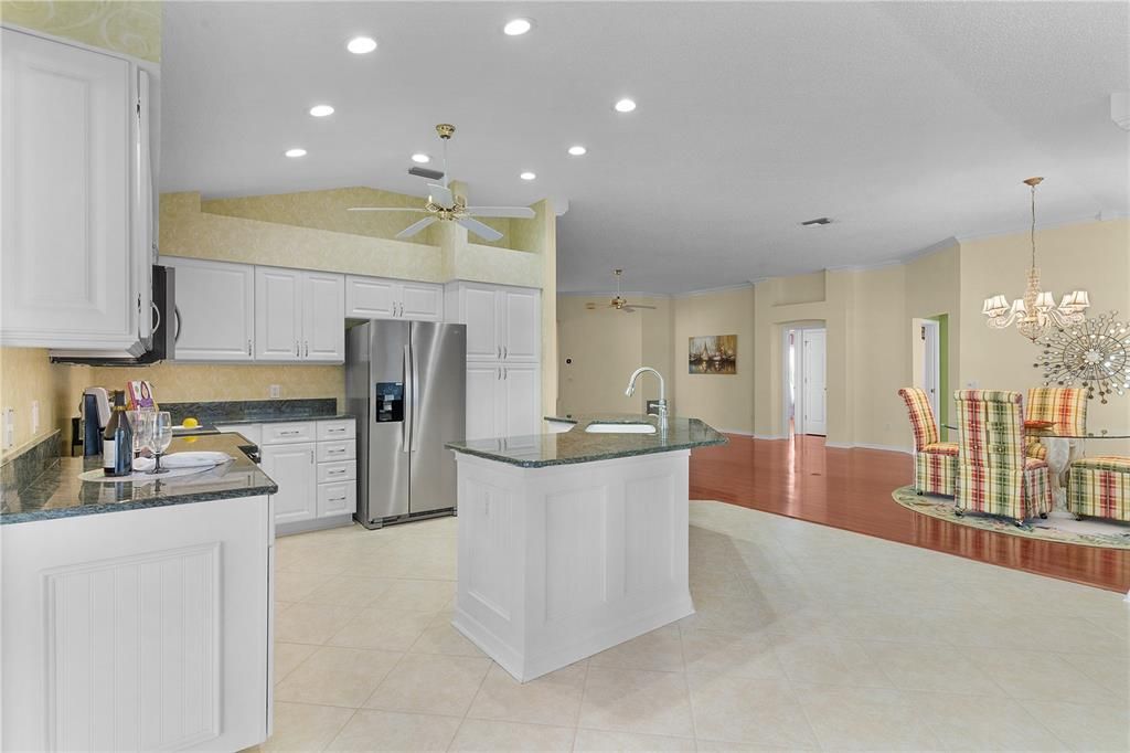 The kitchen features granite countertops, white cabinets with glass inserts, stainless steel appliances