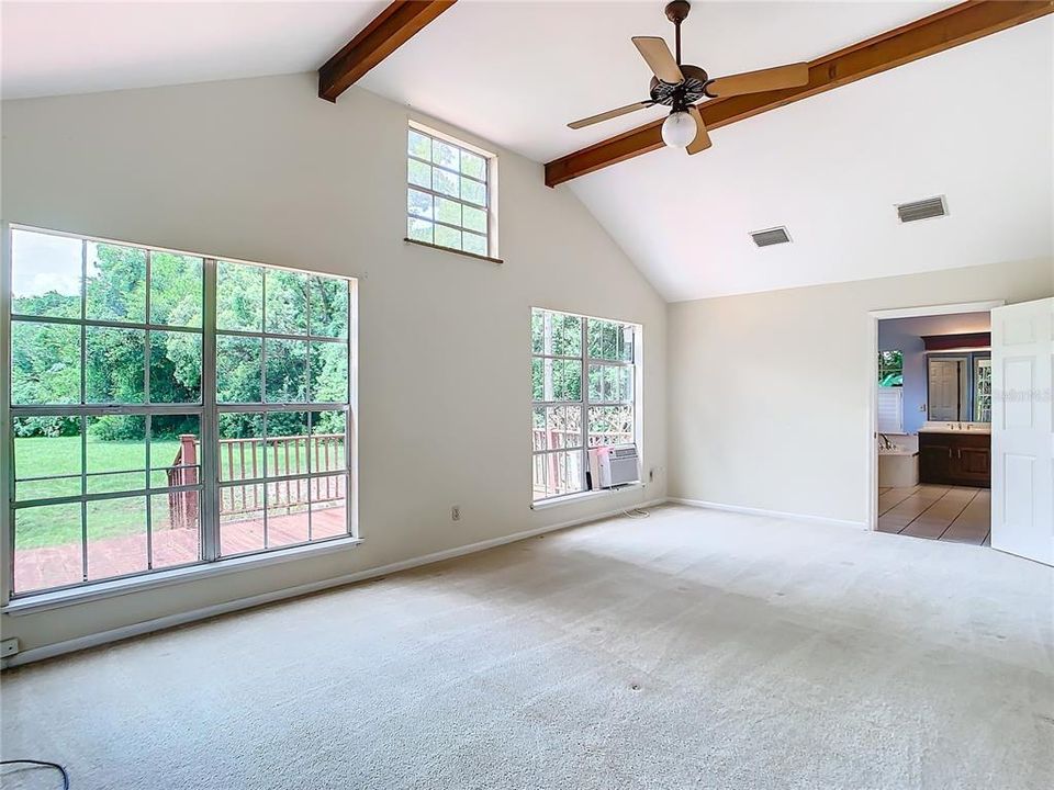 Large primary bedroom with beams faces the lake.