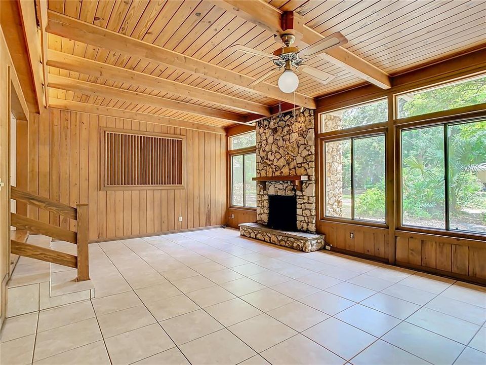 Family room with a wood burning fire place and windows with a park-like setting view.