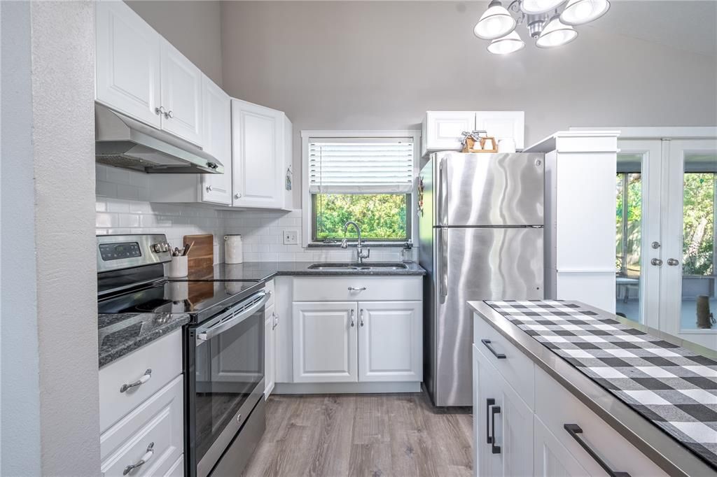 The kitchen features an abundance of cabinets and drawers, a granite counter top and subway tile backsplash.